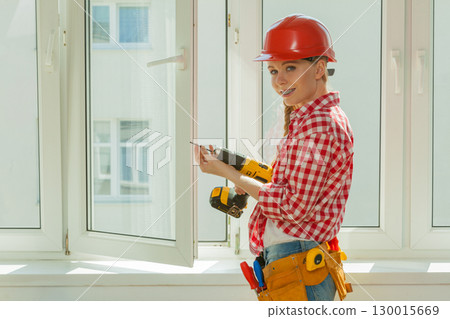 Woman using drill on window 130015669