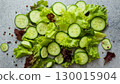 Fresh green salad with cucumber, arugula, red onion and spices on grey background 130015904
