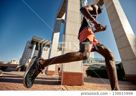 Athlete running through modern urban landscape on a sunny day 130015999