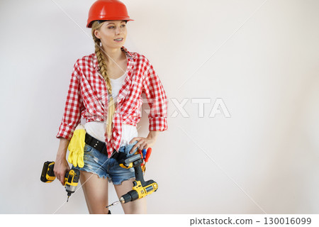 Woman wearing helmet using drill 130016099