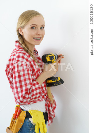 Woman drilling in wall Woman drilling in wall 130016120