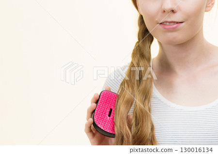 Blonde girl brushing her long hair 130016134
