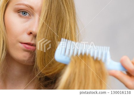 Blonde girl combing her long messy hair Blonde girl combing her long messy hair 130016138