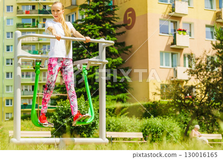 Woman doing exercise in outdoor gym Woman doing exercise in outdoor gym 130016165
