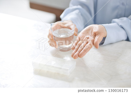 Hands of a middle-aged woman taking medicine 130016173