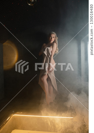 Woman enjoys a serene moment in a sauna while relaxing and unwinding Woman enjoys a serene moment in a sauna while relaxing and unwinding 130016480