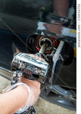 Man driver hand refilling the car with fuel at the gas petrol station.  130016702