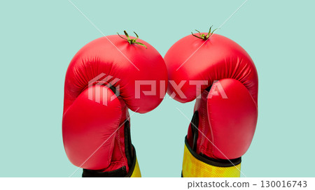 Red boxing gloves styled as fresh tomatoes against green background 130016743