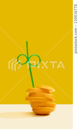Orange slices stacked with green straw on yellow background 130016778