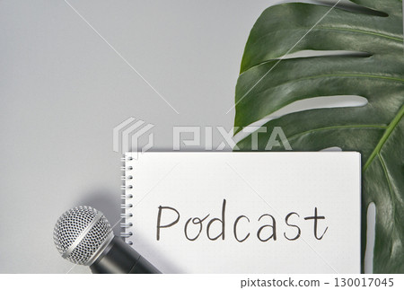 Microphone and notebook with podcast text on gray background featuring large Microphone and notebook with podcast text on gray background featuring large 130017045