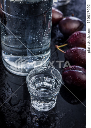 Distilled alcohol and plums on black table. Plum brandy shot. Distilled alcohol and plums on black table. Plum brandy shot. 130017092