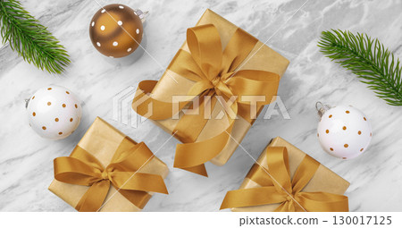 Gift box with red gold bow ribbon with ball and leaves decor on marble table, christmas background 130017125