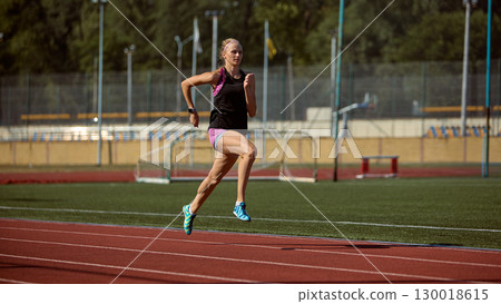 Athletic woman running on outdoor track with powerful stride and focus. Athletic woman running on outdoor track with powerful stride and focus. 130018615