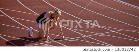 Female sprinter prepares to race on a track with intense focus and determination. Banner 130018748