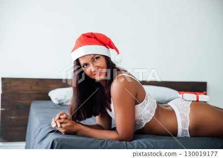 Woman in lingerie with gift in bedroom on bed for new year Woman in lingerie with gift in bedroom on bed for new year 130019177