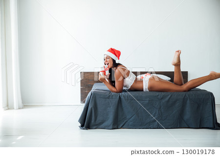 Woman in lingerie with gift in bedroom on bed for new year 130019178