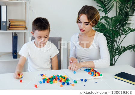 teacher engaged with boy educational games on the table 130019308
