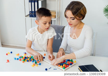 teacher engaged with boy educational games on the table 130019309
