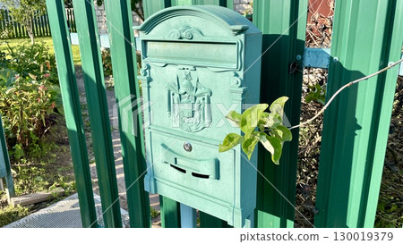 Ornate Green Mailbox on a Fence 130019379