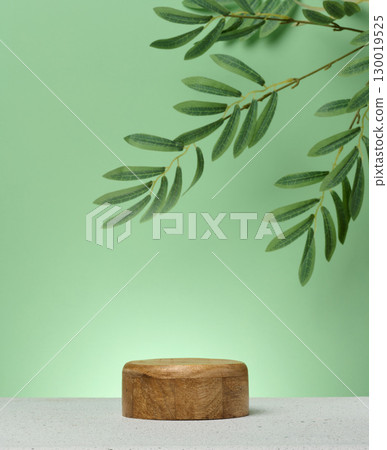 Wooden cylindrical podium or display stand sits on green background. 130019525