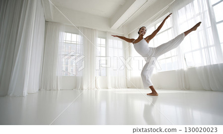 Graceful Ballet Dancer Practicing Balance in Bright Studio Space 130020023