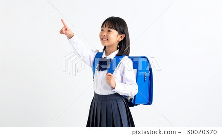 Smiling female elementary school student pointing, studio shot on white background 130020370