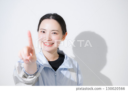 一位身穿運動服的女子歡呼著，看著鏡頭，微笑著，指著數字 1 130020566