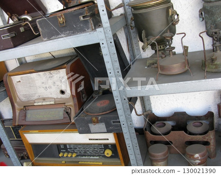 A collection of vintage audio players and metal cookware arranged on shelves, blending musical history with culinary relics in a rustic setting 130021390