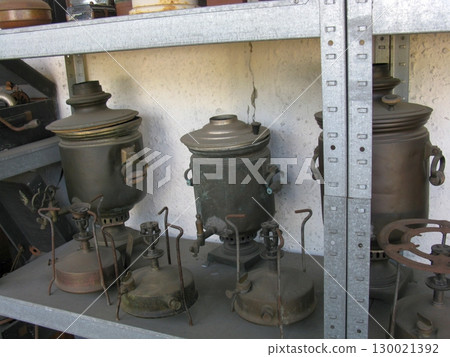 A row of antique metal samovars with ornate spouts and stands, lined up on a shelf, reflecting the rich tradition of old world tea preparation 130021392