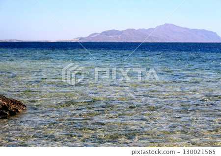 Coastal Scene with a Solitary Rock in Shallow Water and Mountain Backdrop Coastal Scene with a Solitary Rock in Shallow Water and Mountain Backdrop 130021565