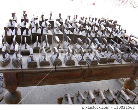 Extensive Collection of Vintage Irons Displayed Neatly on a Wooden Table 130021568