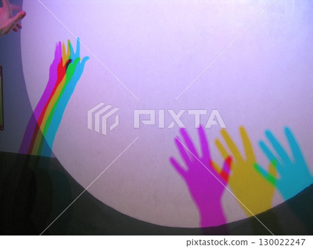 Multicolored Hand Shadows in Vibrant Hues Cast on a Curved Purple Surface 130022247