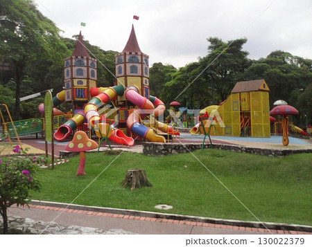 A Castle Shaped Play Structure with Colorful Slides in a Lush Park Setting 130022379