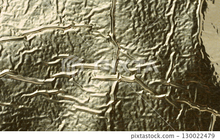 Texture of shiny gold foil with numerous wrinkles and folds. 130022479