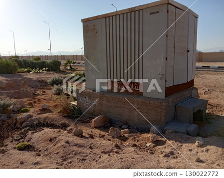 Weathered Utility Box in a Desert Landscape with Sparse Vegetation and Rocks 130022772