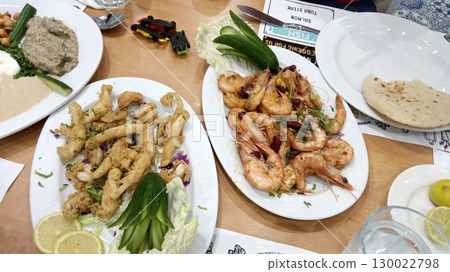 Seafood Feast on a Table with Grilled Shrimp, Fried Squid, and Fresh Veggies Seafood Feast on a Table with Grilled Shrimp, Fried Squid, and Fresh Veggies 130022798