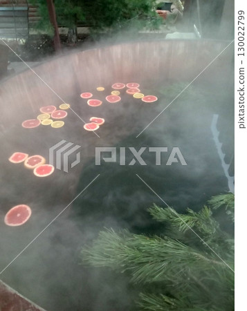 Steamy Hot Tub with Floating Citrus Slices and Pine Branches in a Relaxing Setting Steamy Hot Tub with Floating Citrus Slices and Pine Branches in a Relaxing Setting 130022799