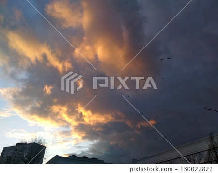 A Fiery Sunset with Birds Soaring Over Urban Rooftops Amidst Dramatic Clouds A Fiery Sunset with Birds Soaring Over Urban Rooftops Amidst Dramatic Clouds 130022822