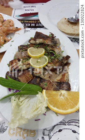 A Flavorful Grilled Fish Platter with Lemon Slices and Fresh Greens on a Festive Table A Flavorful Grilled Fish Platter with Lemon Slices and Fresh Greens on a Festive Table 130022824