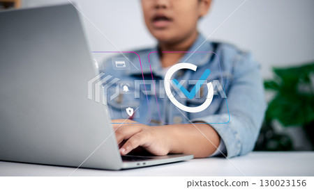 Person working on laptop with checkmark, security, payment, and notification icons symbolizing online approval, digital transactions, and cybersecurity 130023156