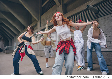 Redhead female dancer moving forward with confidence during street choreography 130023567