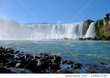 View of a beautiful waterfall from a rocky shore 130023585