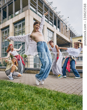 Female street dancer smiling with energy while leading friends in urban choreography 130023588