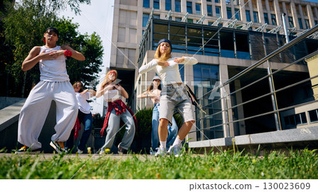 Street dance crew performing routine on city square with energy and confidence 130023609