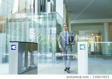 A businessman in a suit walking through the office entrance. Photo courtesy of Sky Perfect Tokyo Media Center. 130023915