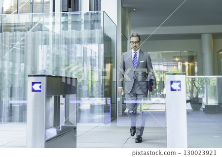 A businessman in a suit walking through the office entrance. Photo courtesy of Sky Perfect Tokyo Media Center. 130023921