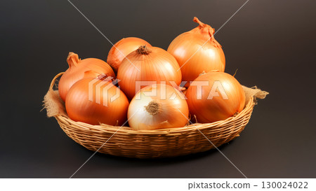 Basket of fresh raw onions in a woven basket on dark background 130024022
