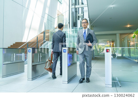 A businessman in a suit walking through the office entrance. Photo courtesy of Sky Perfect Tokyo Media Center. 130024062