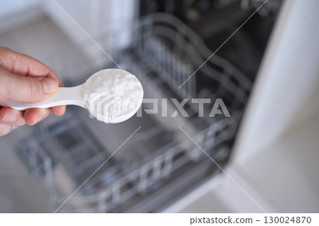 Hand holding dishwasher salt spoon against open dishwasher interior Hand holding dishwasher salt spoon against open dishwasher interior 130024870