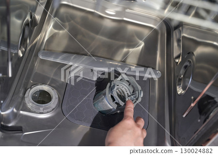 Female hand cleaning stainless steel dishwasher filter inside open appliance Female hand cleaning stainless steel dishwasher filter inside open appliance 130024882